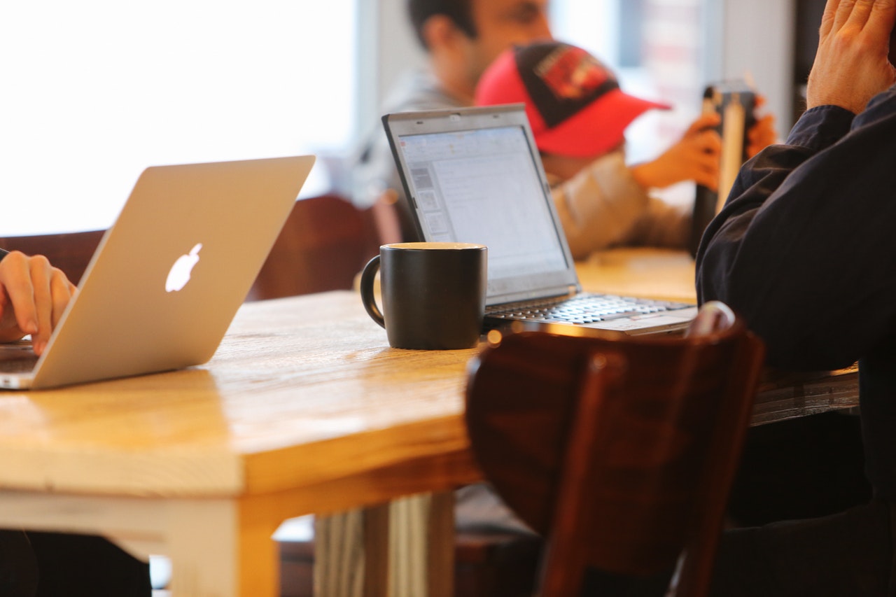 people sitting at a table working on their laptops and drinking coffee.