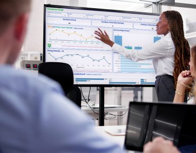 Woman pointing at recruiting dashboard in hiring team meeting