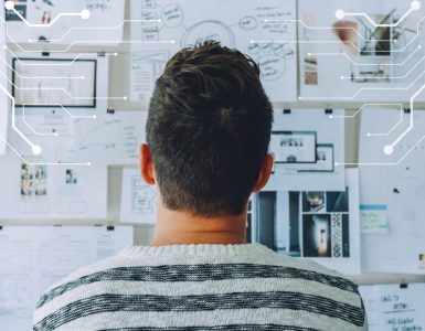 Man looking at wall of recruitment plans on paper considering how to use AI